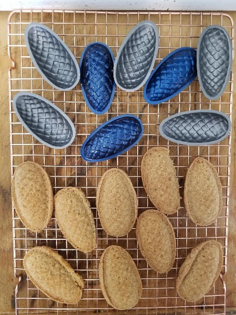 Various oval-shaped loaves of bread cooling on racks.