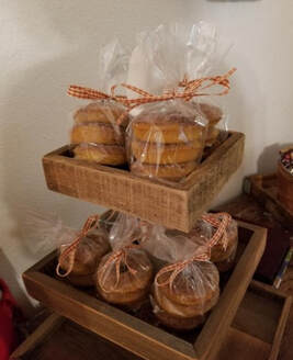 Two-tiered display of baked goods wrapped in clear plastic and tied with orange ribbons.