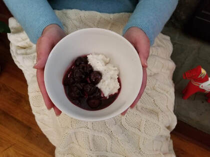 A bowl with yogurt and fruit compote held by hands.