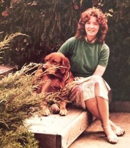 Woman sitting on a bench with a golden retriever dog in a garden.
