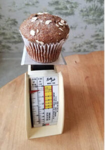 A chocolate muffin on a kitchen scale.