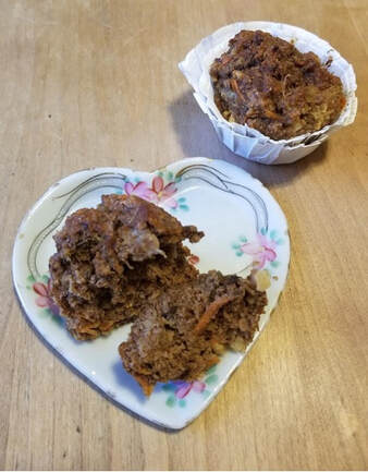 Two chocolate muffins, one halved, on a floral heart-shaped plate.