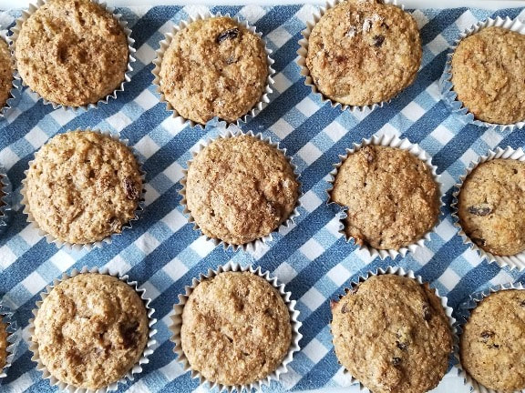 Nine crumb-topped muffins on a blue and white checkered cloth.