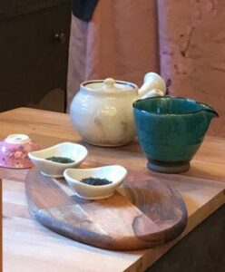 Table set with sauces, a green bowl, and a ceramic jar on a wooden surface.