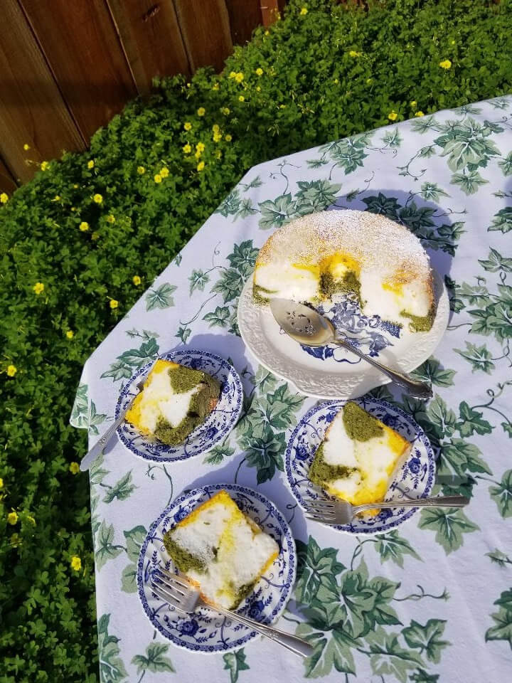 Lemon cake on a floral tablecloth with matching plates and spoons outdoors.