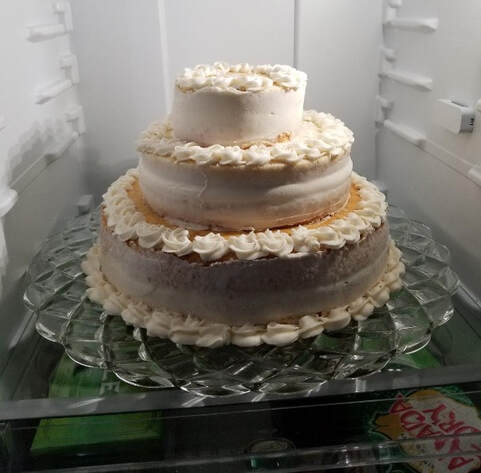Three-tier white frosted cake with decorative icing on a glass plate.