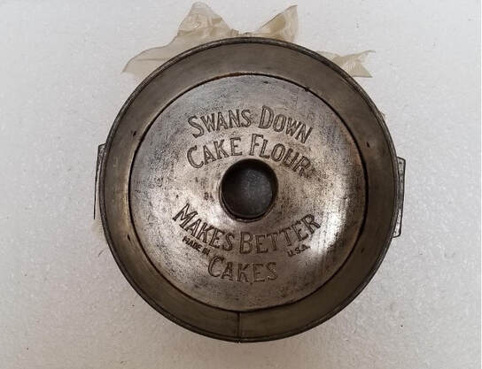 Vintage metal cake flour tin with engraved text.