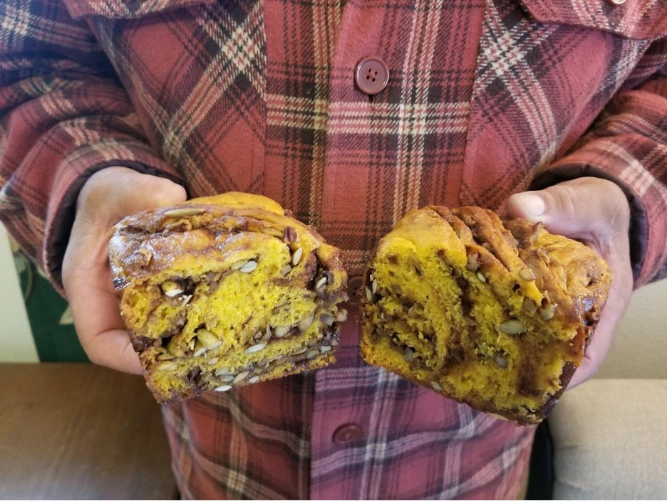 Person holding a sliced loaf of cinnamon swirl bread.