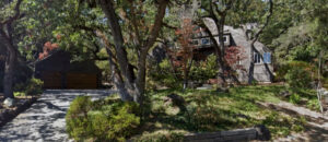 Rustic house surrounded by lush greenery and autumn trees.