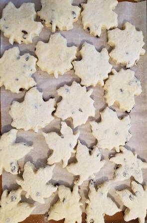 Snowflake-shaped cookies with chocolate chips on parchment paper.