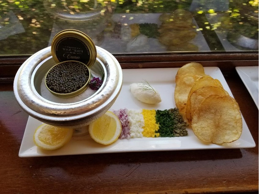 Gourmet caviar served with lemon, potato chips, and traditional accompaniments.