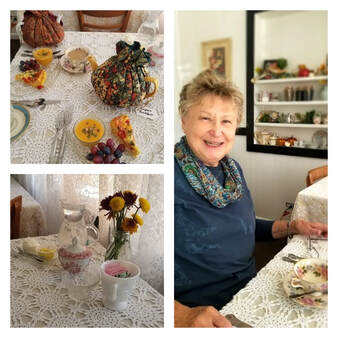 A cheerful elderly woman enjoying tea with a beautifully set table.