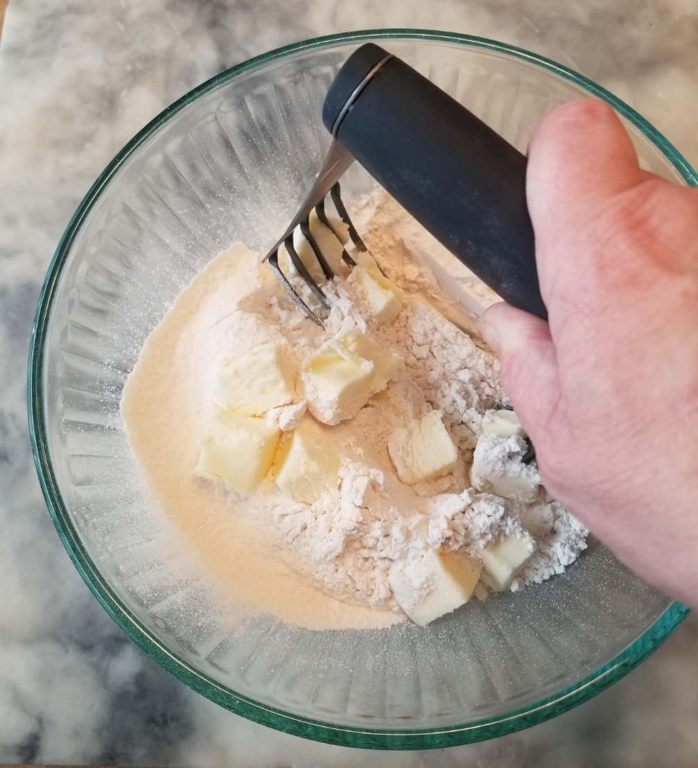 Hand whisking batter ingredients in a glass bowl.