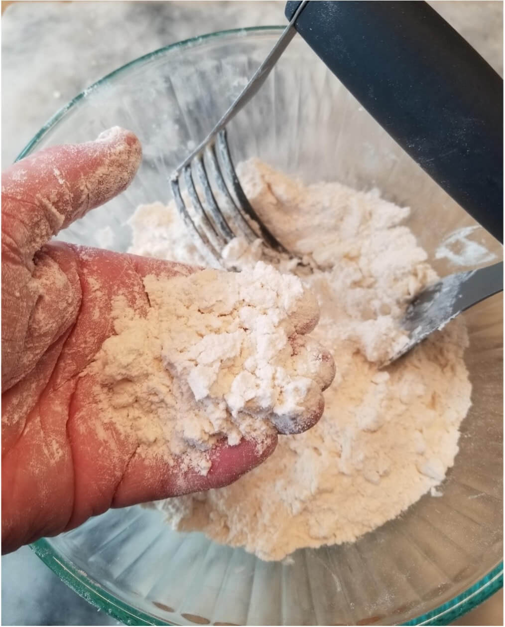 Hand mixing flour with dough using fork and knife.