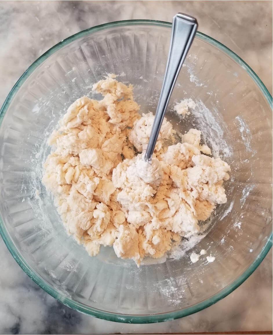 Mixing dough in a glass bowl with a spoon.