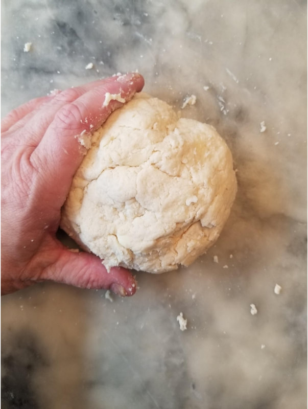 Hand shaping dough on a floured surface.