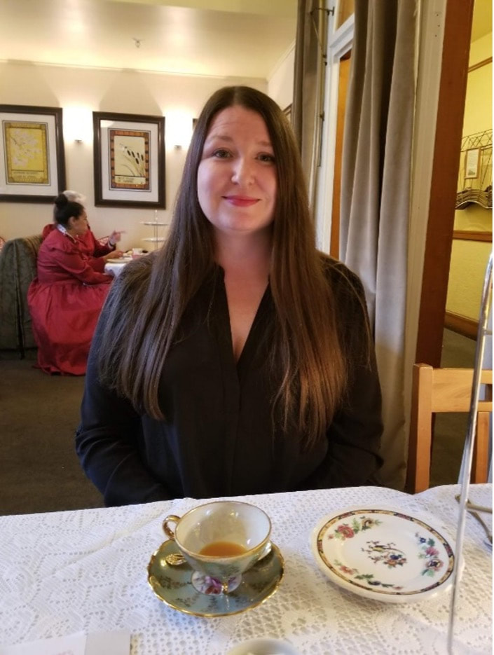 Woman sitting at a table in a cozy café with a cup of tea.