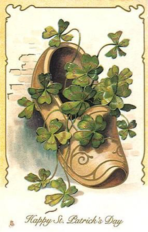 An old shoe filled with green clovers against a textured wall.