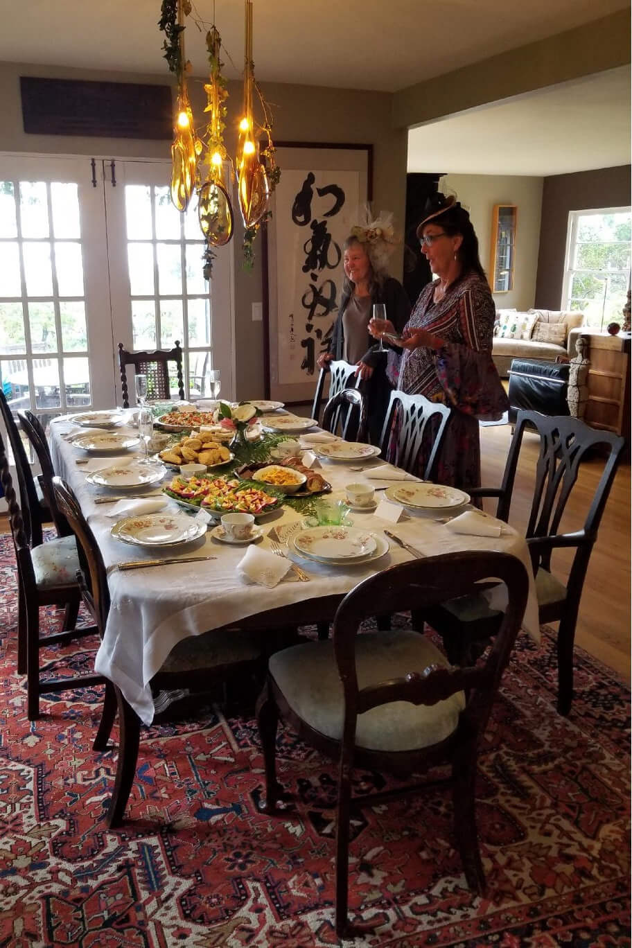 A dining table set with plates and food, a woman standing nearby.
