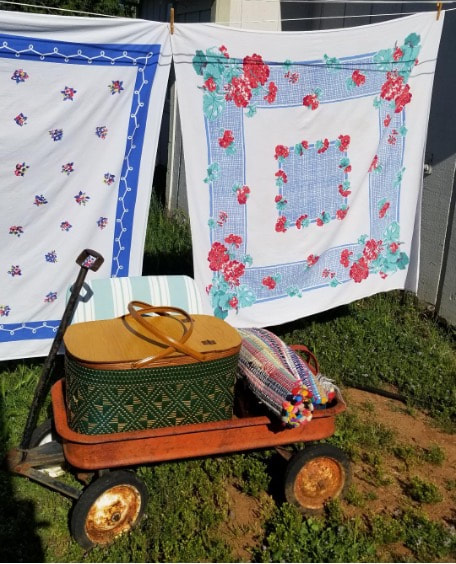 Vintage wagon with a picnic basket and a blanket outdoors.