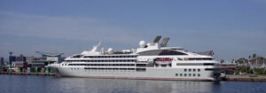 A large white cruise ship sailing on calm waters under a clear blue sky.