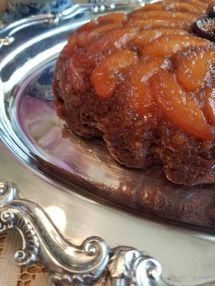 Close-up of a glazed pineapple upside-down cake on a silver tray.