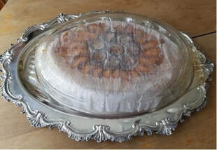 Elegant silver platter with a covered dessert inside.