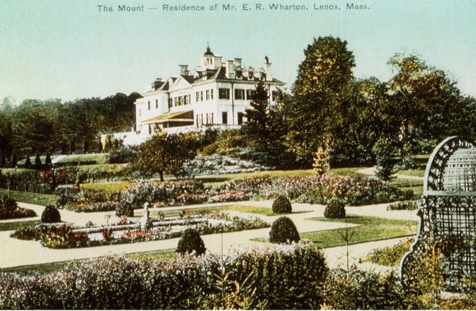 Historic mansion with ornate gardens under a blue sky.