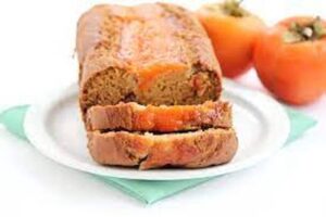 Sliced carrot bread on a plate with whole carrots in the background.