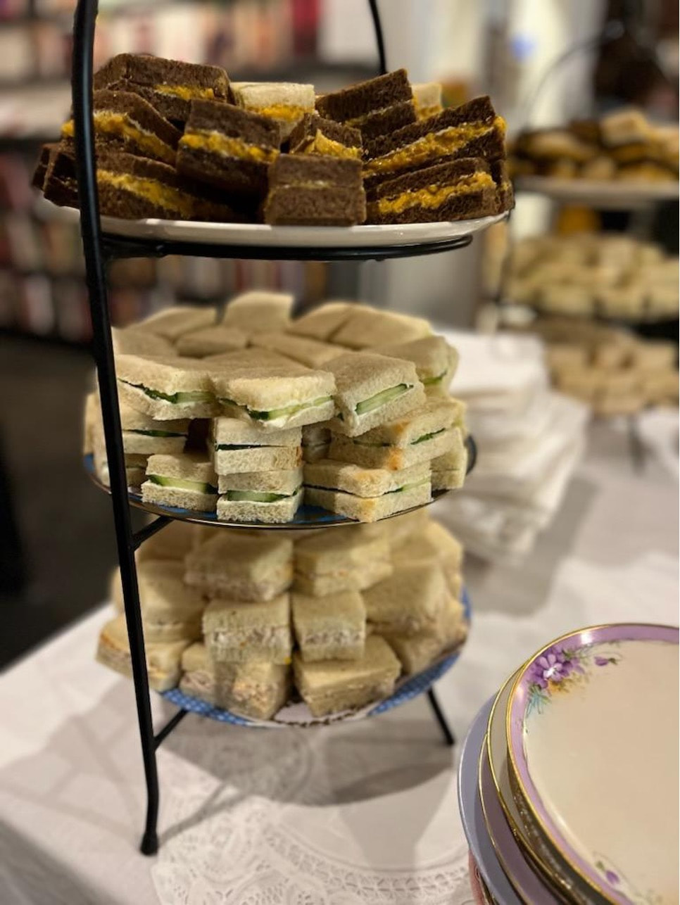 Assorted finger sandwiches arranged on a tiered serving tray at an event.