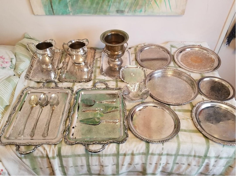 Vintage silverware set including trays, spoons, and cups arranged on a table.