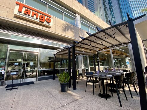 Outdoor seating area of a modern restaurant in a city setting.