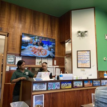 Two staff members wearing masks behind a counter in a cozy restaurant.
