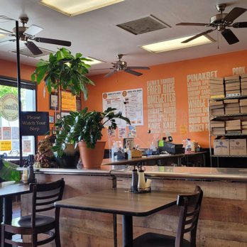 Cozy cafe interior with plants and menu boards on peach walls.
