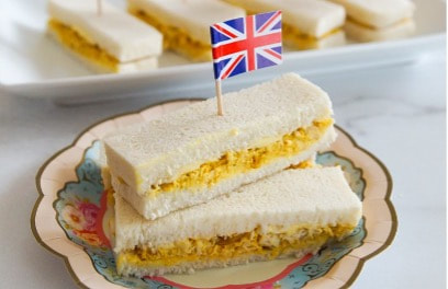 Curried egg sandwich with a British flag toothpick on a decorative plate.
