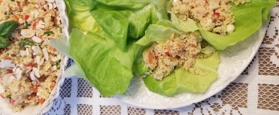 Lettuce wraps filled with a seasoned quinoa mixture on a white plate.