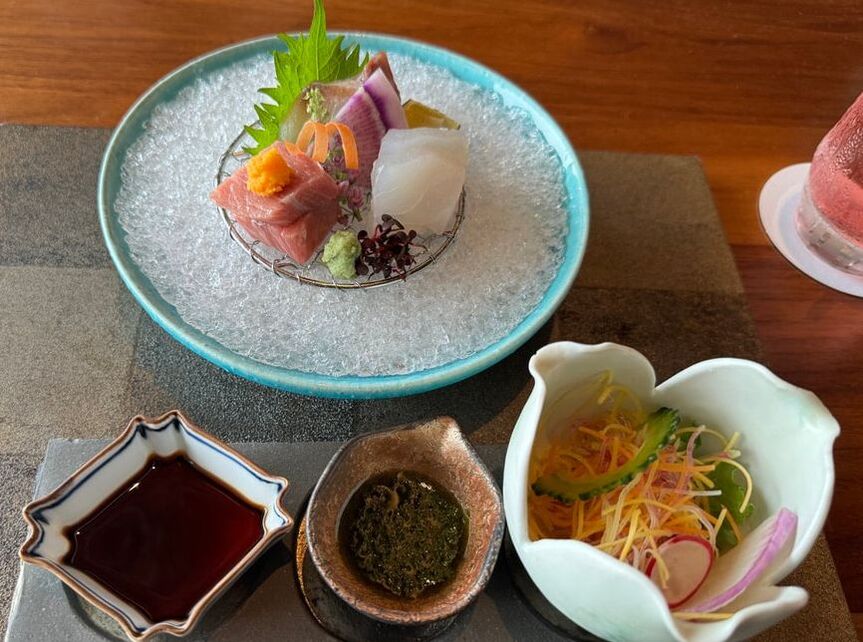 Elegant sashimi platter with fresh fish, seaweed, and dipping sauces.
