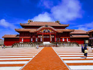 The vibrant red Shuri Castle under a bright blue sky.