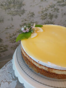 A lemon-glazed cheesecake with a flower and leaf garnish.