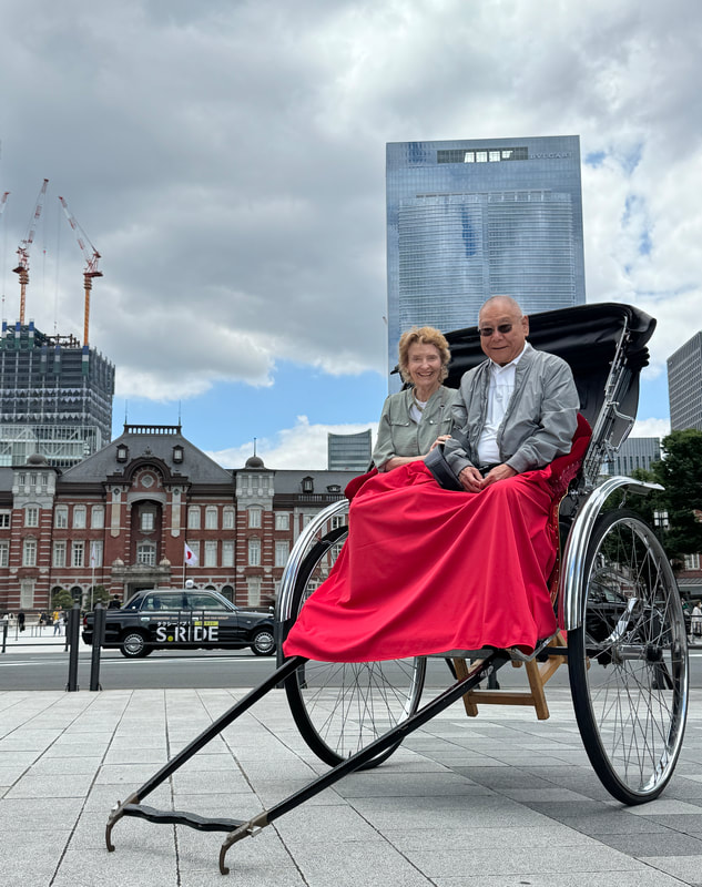 Elderly couple enjoying a ride on a traditional rickshaw in an urban setting.