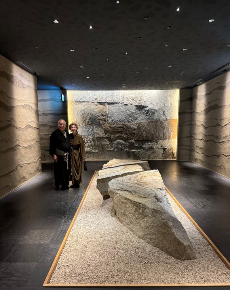 Two people standing in a dimly lit museum exhibit with ancient artifacts.