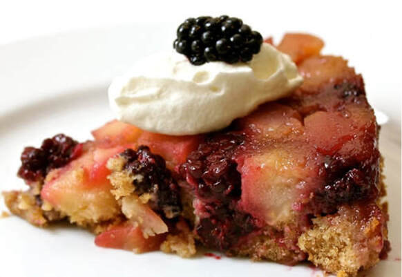 Close-up of a blackberry tart topped with whipped cream.
