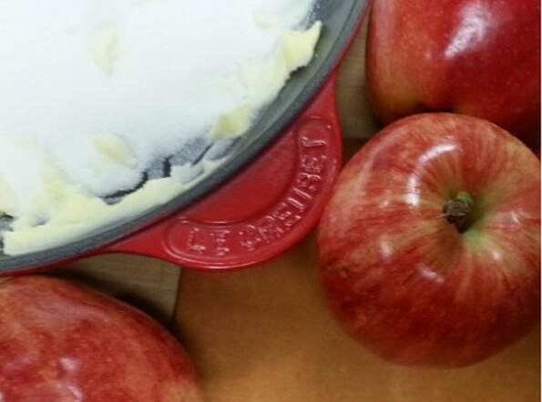 Fresh red apples surrounding a bowl with butter.