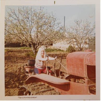 Person cooking outdoors near an old tractor in a rustic setting.