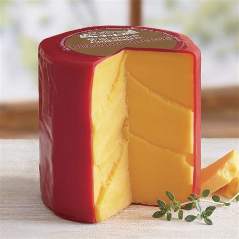 A large block of cheese with a red wax rind and a wedge cut out.