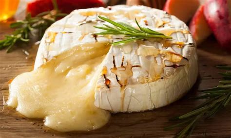 Grilled camembert cheese with melted interior and rosemary garnish.