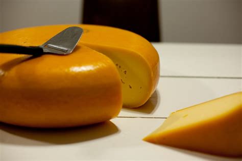 A round cheese wheel with a wedge cut out on a table.