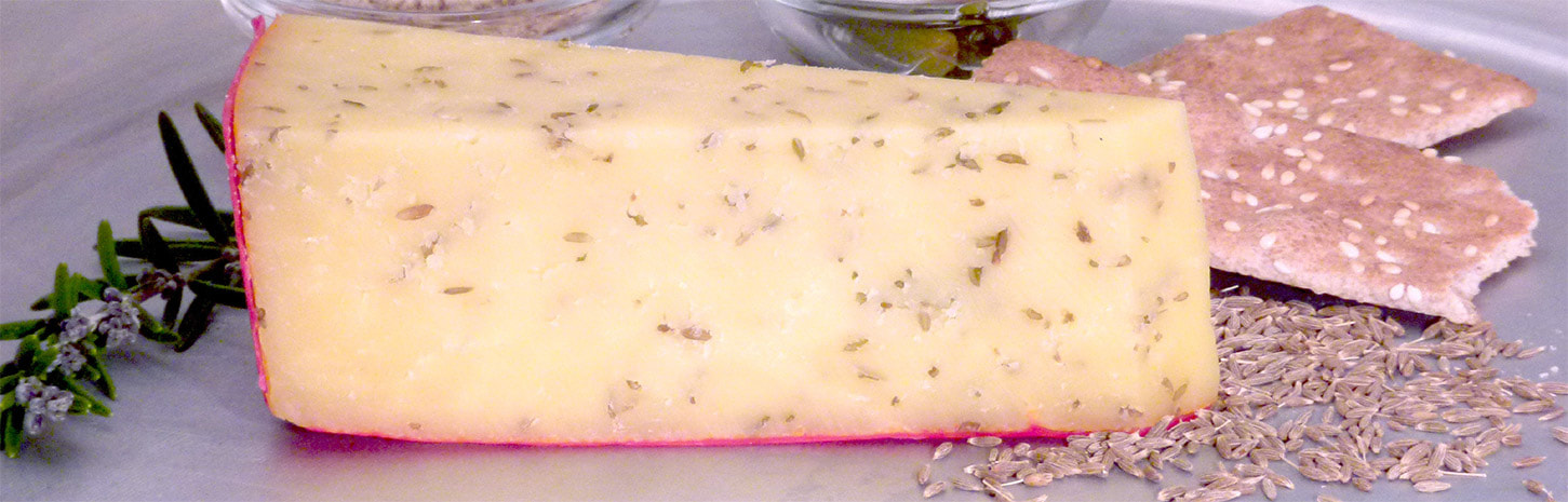 Close-up of herb-infused cheese with a red rind.