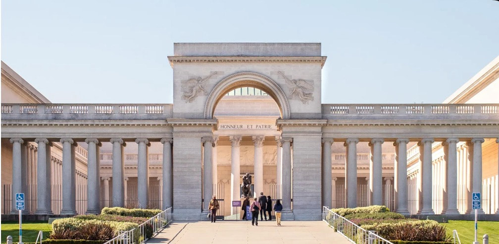 Elegant stone archway with people walking through it on a sunny day.