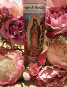 Religious candle surrounded by pink roses.